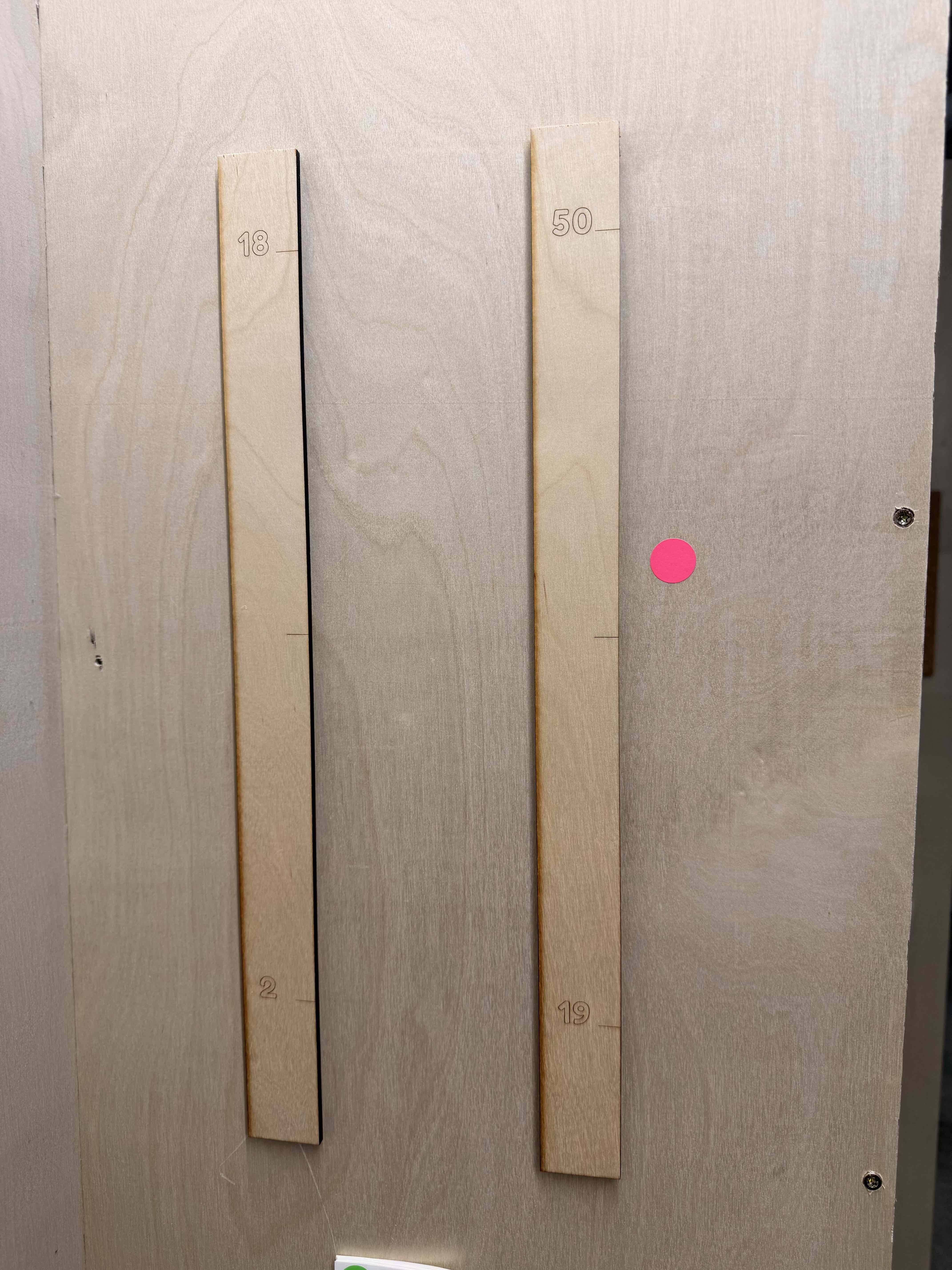 Two laser-engraved wooden rulers marked with ages 2 to 19 and 18 to 50 with a pink sticker