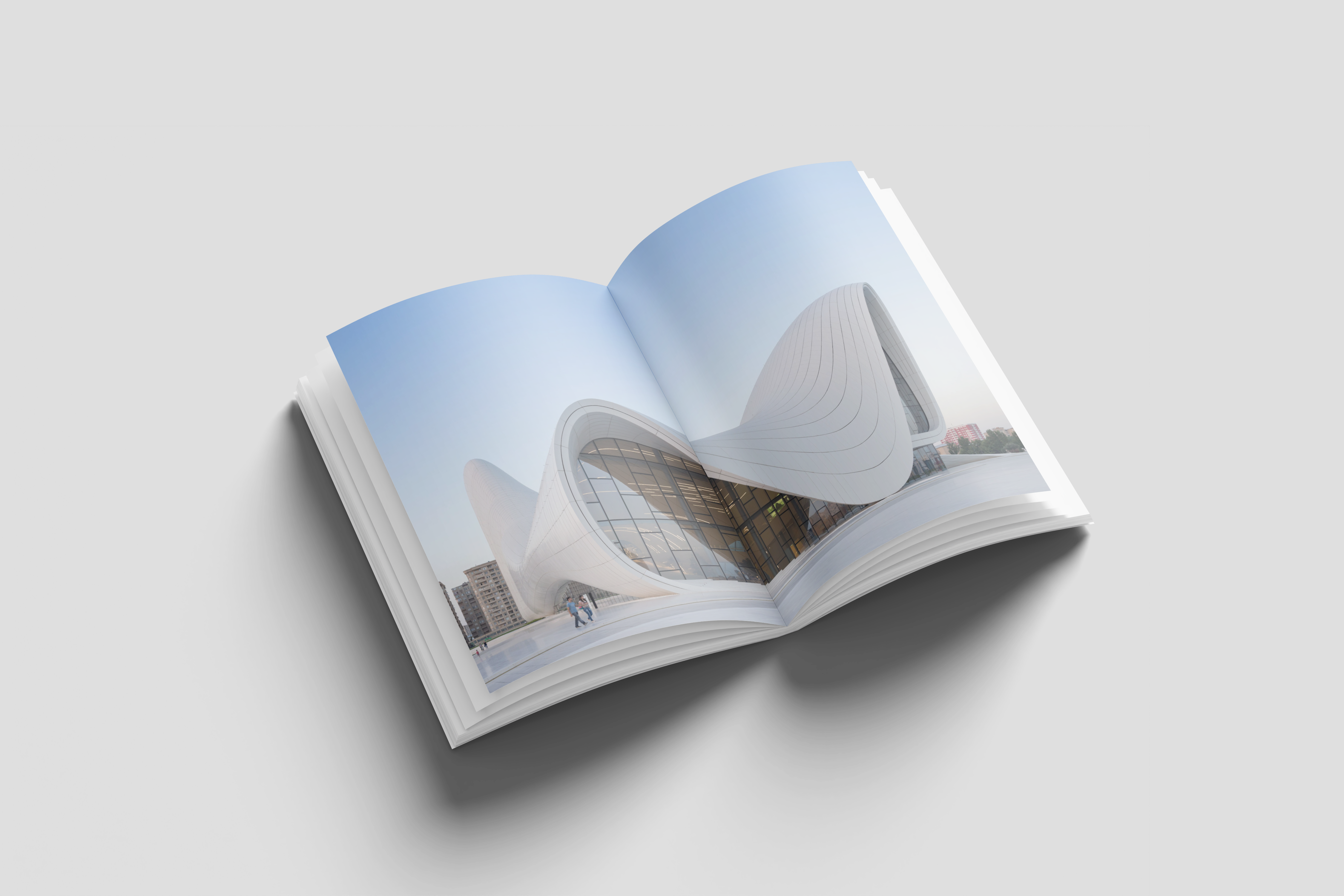 Open book with a full-bleed photograph of a curved white building under a pale blue sky across both pages
